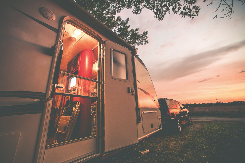 The exterior of a travel trailer with the sunset in the background. 