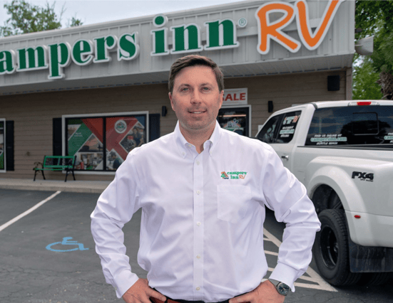 Daniel stands in front of a Campers Inn storefront
