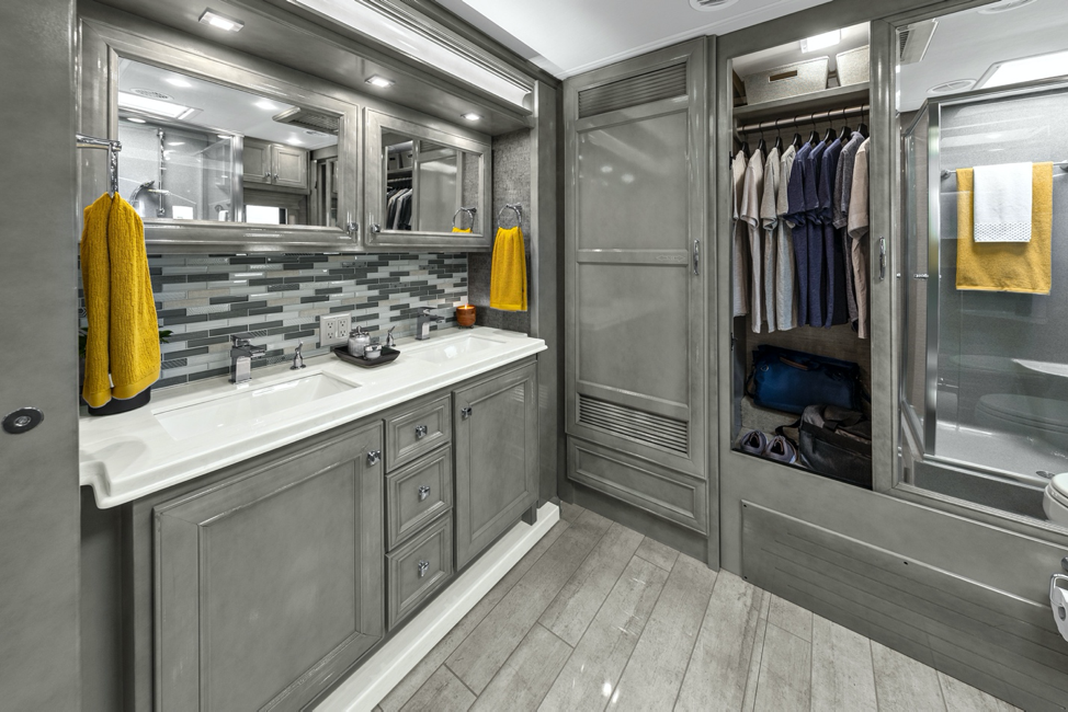 The master bath of a Tiffin Phaeton featuring sterling cabinets and coastal sand décor.