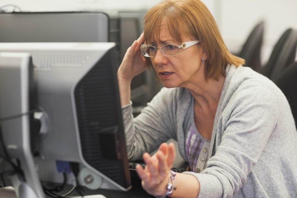 Angry mature student working with computer in computer class.jpeg