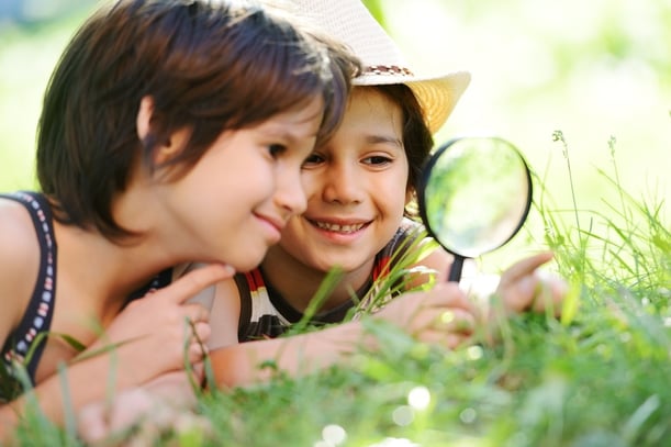 Happy kid exploring nature with magnifying glass.jpeg