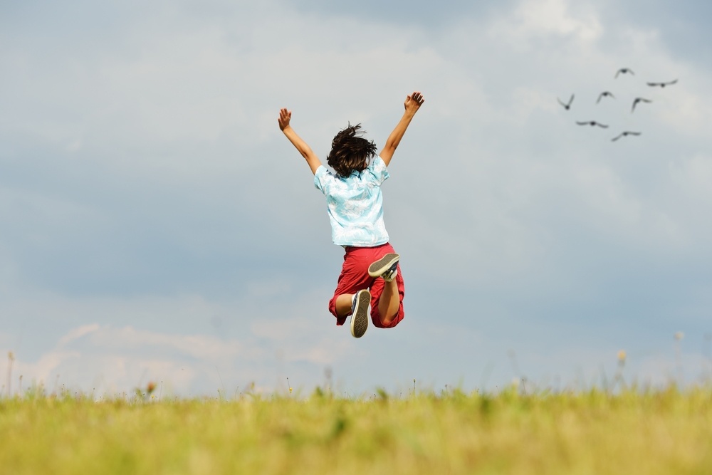 Happy little boy on summer grass meadow in nature jumping.jpeg