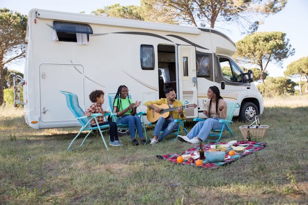 Family plays guitar and hangs out beside their RV