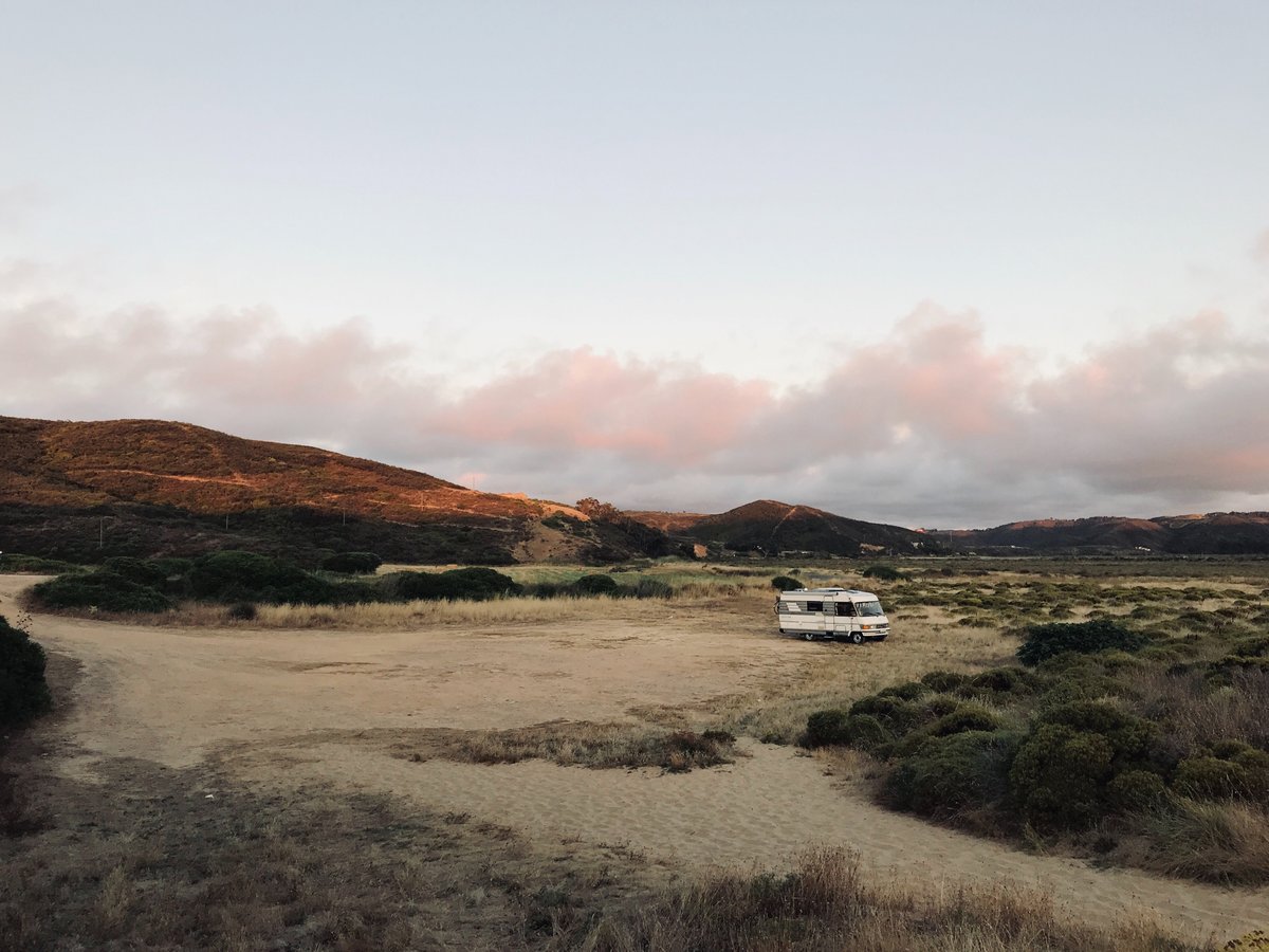 Motorhome out in a desert landscape with a sunset in the background