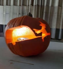 A witch pulling an RV carved on a pumpkin jack-o-lantern