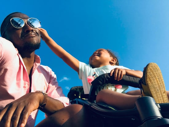 Baby in stroller pinches Dad's cheek