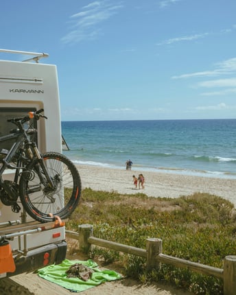 An RV parked by the beach with towels and bikes around it