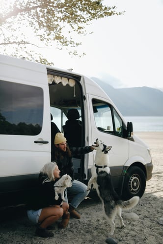Couple plays with their two dogs in the doorway of their rvs at the beach
