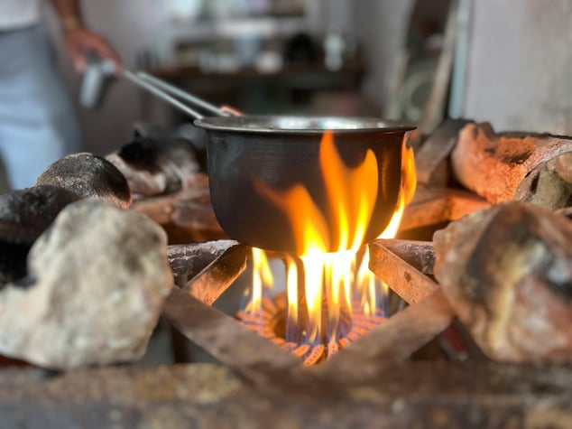 A cooking pot sits on a campfire