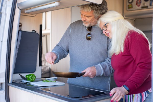 older couple cooks veggies in their rv