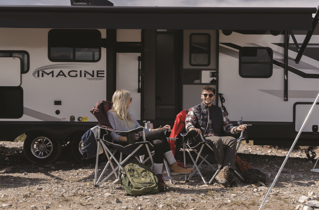 two campers set up in front of a grand design imagine travel trailer