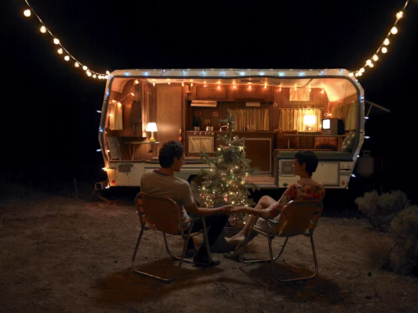 couple holds hands in front of festive camper