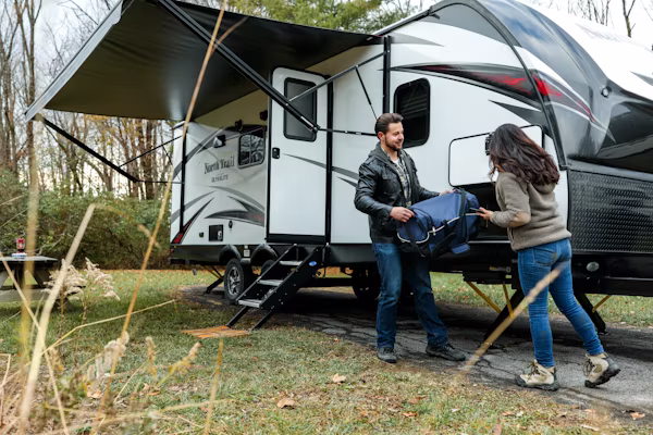 couple_loads_camping_equipment_into_rv_in_field-1